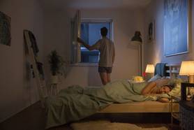 Paar im Schlafzimmer mit Insektenschutz-Spannrahmen von Neher am offenen Fenster