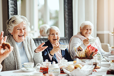 Ältere Damen sitzen lachend zusammen am Tisch bei Kaffee und Kuchen