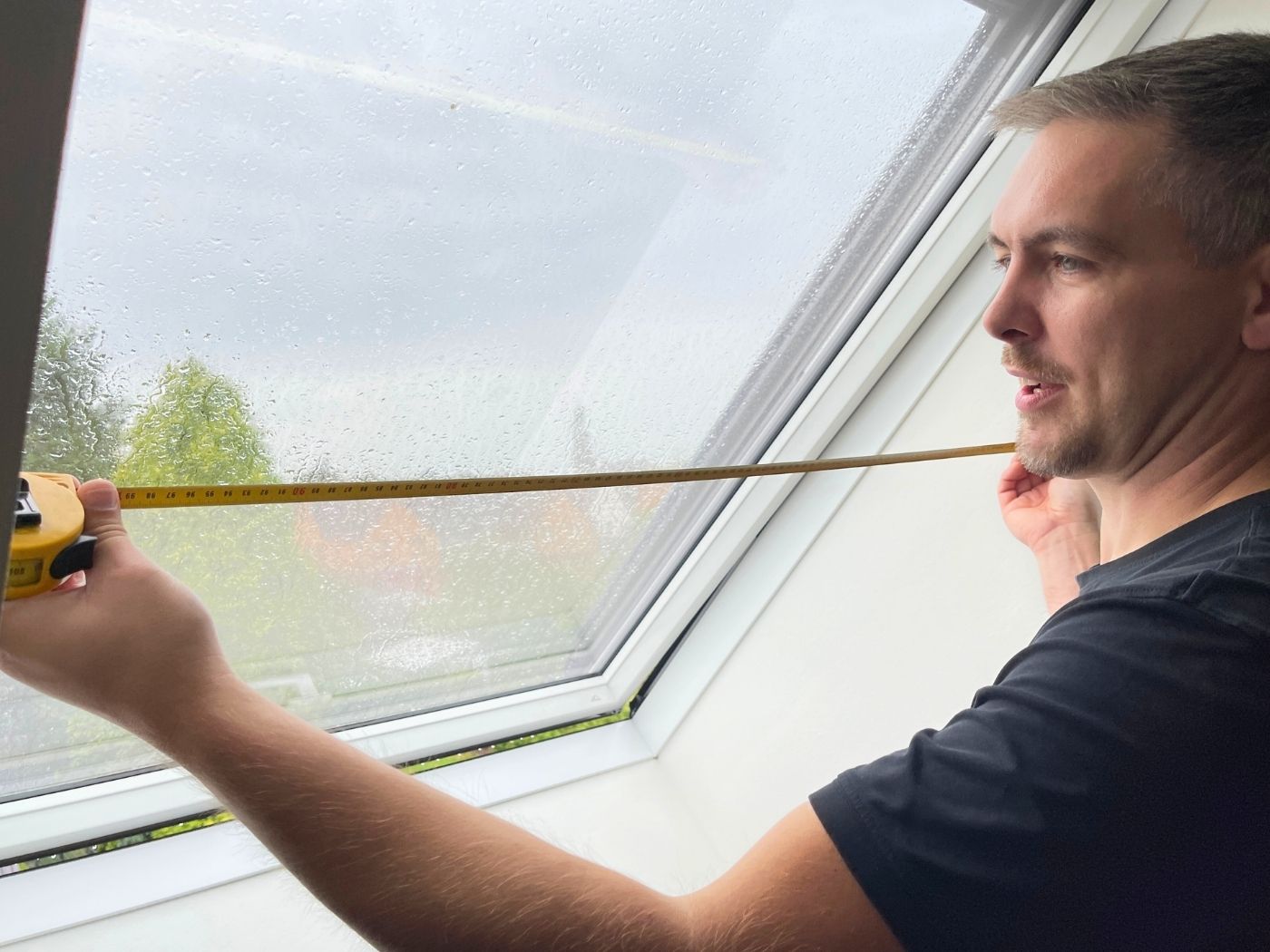 Ein Insektenschutz-Technicker von Schulz-Dobrick nimmt Aufmaß an einem Dachfenster